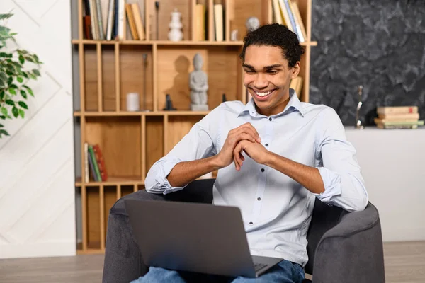 Smart and intelligent millennial multiracial guy in smart casual shit sitting with laptop — 스톡 사진