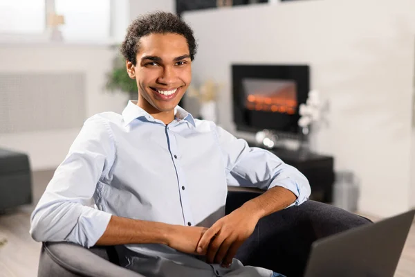 Smiling intelligent multiracial male freelancer in smart casual shirt using laptop for work — Stock Photo, Image