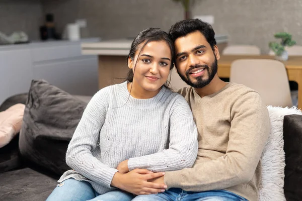 Мультиетнічна пара закоханих орендує будинок разом. Щасливі індійські молодята переїхали в нову квартиру, сидячи на дивані в обіймах. — стокове фото