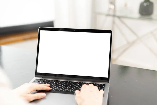 Cropped view of the young woman using laptop for work indoors. Blank white laptop screen for inserting text — стоковое фото