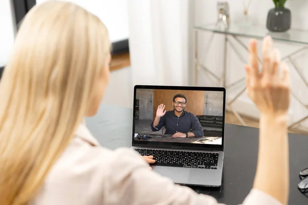 Back view on woman waving with her hand while talking with male employee via video call. Several webcam shot of guy on laptop screen. App for video meeting — стоковое фото