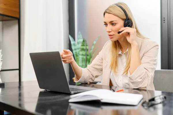 Video conference from home, morning meeting remotely. Young woman using headset for online communication, talking and using laptop — Foto Stock