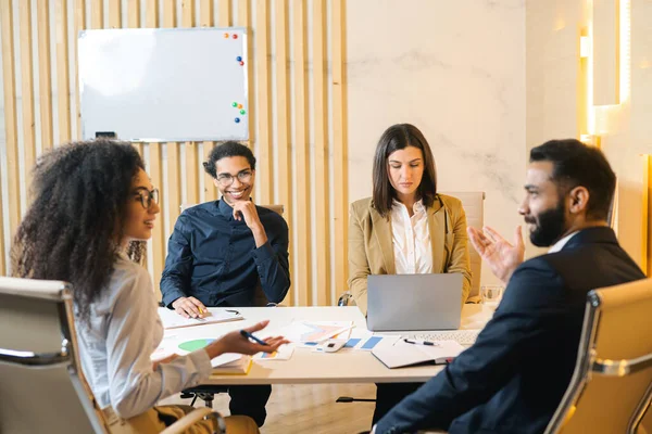 Multiracial team. Group of ambitious young people in smart casual wear discussing business tasks while sitting at the table in a modern office — Foto Stock
