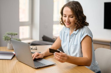 Bilgisayarın başında oturmuş gülümseyen Kafkas ergen kız, online işlem yapmak için kredi kartı numarasını giriyor. Yemek sipariş eden kadın.