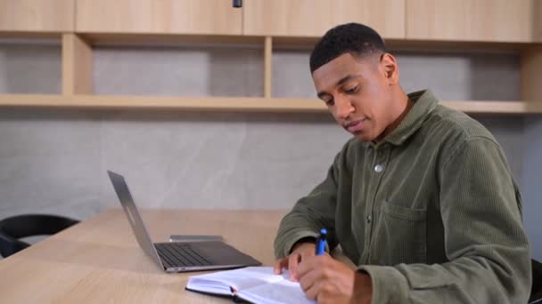 Концентрированный латинский студент смотрит на дисплей ноутбука, решает бизнес-задачи — стоковое видео