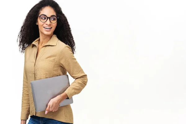 Heureuse jeune femme multiraciale vêtue occasionnellement debout et portant un ordinateur portable — Photo