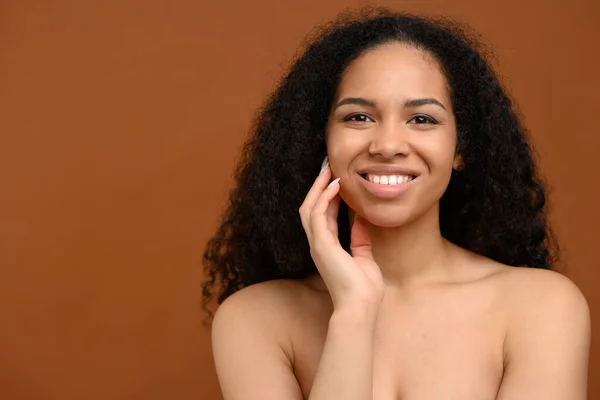 Natural beauty and skincare concept. Young attractive african woman gently touching face and laughing — ストック写真