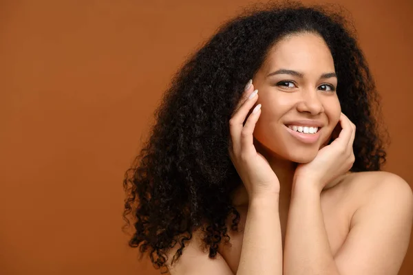 Close-up headshot portrait of cheerful afro woman with naked shoulders touching her face — стоковое фото