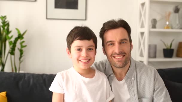 Happy together. Portrait of cheerful father and son sitting on the sofa in cozy living room — Vídeo de Stock