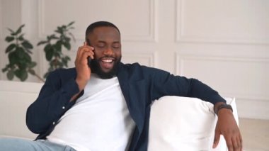 Carefree African-American guy talking at easy on the smartphone