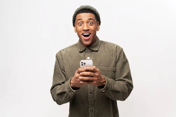Gracioso chico de moda sorprendido de repente leer el mensaje en su teléfono móvil y expresar sorpresa, noticias increíbles en el teléfono inteligente — Foto de Stock