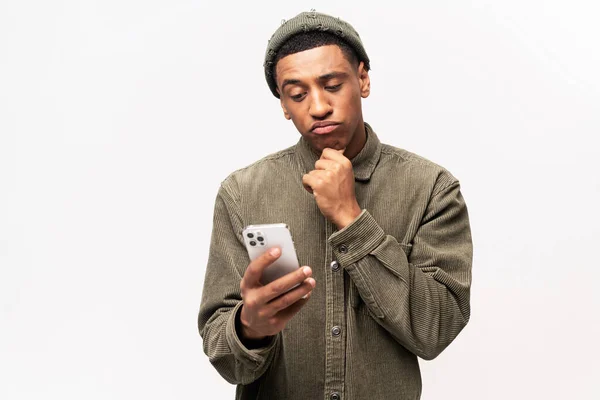 Portrait de l'homme tenant le menton, debout avec smartphone à la main, envisageant la mise à jour du logiciel, choisissant des tarifs appropriés — Photo