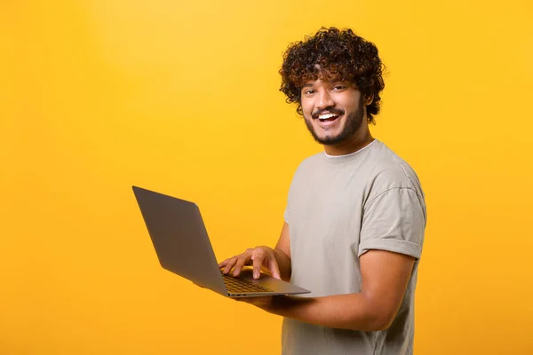 Portrait de jeune latin gars debout isolé sur le mur jaune tenant ordinateur portable — Photo