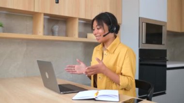 Gülümseyen, çok kültürlü, genç bir kadın uzaktan konuşmak için kulaklık kullanıyor.