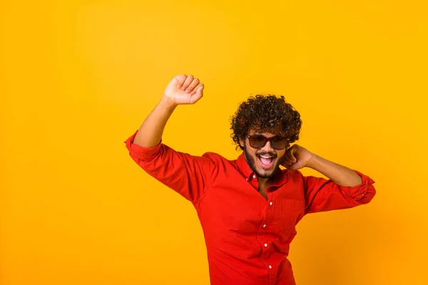 Excited positive bearded hispanic man in stylish clothes dancing, raising hands up and having fun, good mood. Indoor studio shot isolated — Photo