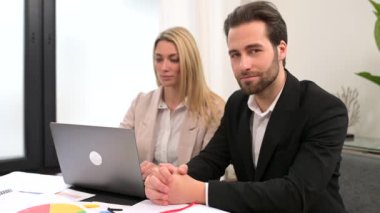 Modern ofiste evraklar ve dizüstü bilgisayarlarla çalışan çekici bir kadın ve erkek.