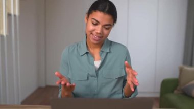 Gülümseyen etnik kadın sanal iletişim için laptop kullanıyor