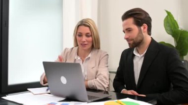 Friendly male and female office workers in formal wear, sitting at the desk in the office,
