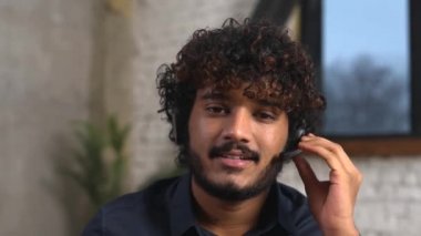 Kulaklık takan, müşterilerle video görüşmesi yapan odaklanmış genç iş adamı.