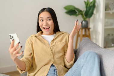 Çok mutlu bir kadın telefon ekranına bakıyor, başarıyı kutluyor. Heyecanlı genç bayan elinde akıllı telefon, mesajda iyi haberler okuyor.