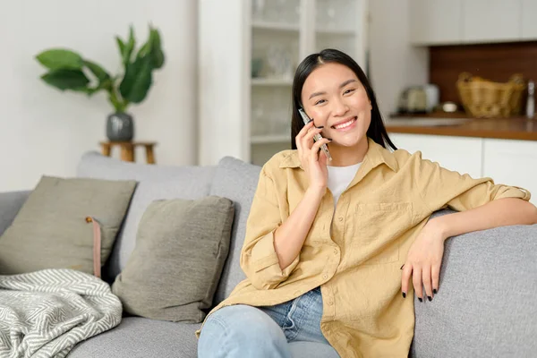 Gülümseyen genç bir kadın cep telefonuyla arkadaşlarıyla sohbet ediyor, keyifli telefon konuşmaları yapıyor.