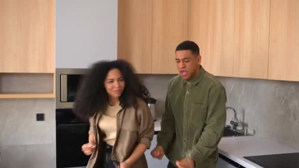 Happy African-American couple dancing in the kitchen, singing while cooking breakfast — Video