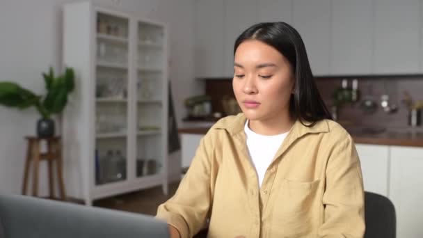 Alegre joven asiática mujer sorprendió victoria y mirando el portátil sentado en casa — Vídeo de stock