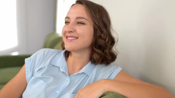 Joyeux plein d'énergie femme en vêtements décontractés reposant sur le canapé avec les mains sous la tête — Video