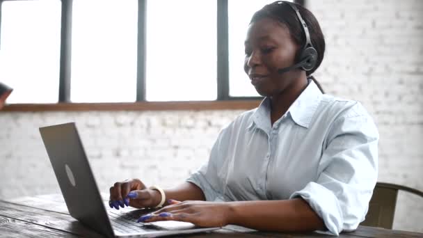 Female African-American support worker wearing wireless headset with mic talking — Vídeo de stock