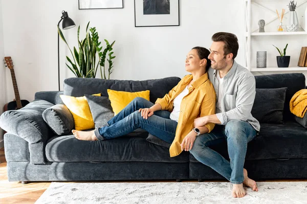 Concept of support and caring in marriage. Gentle and lovely mid-aged couple in love sitting in embrace on the comfortable sofa at home — Fotografia de Stock