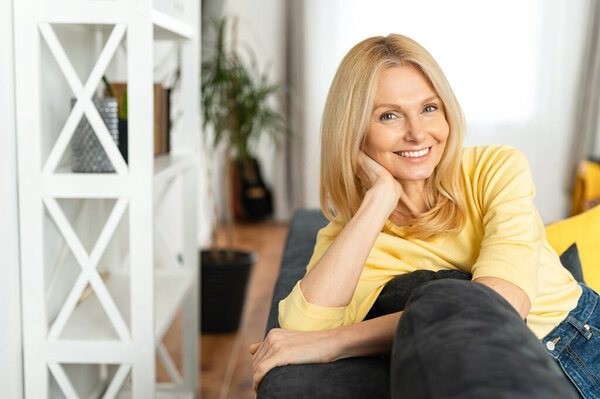 Фото улыбающейся пожилой белой женщины, смотрящей в камеру. Веселая беззаботная женщина отдыхает дома