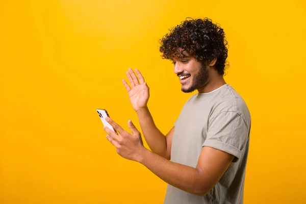 Nadšený kudrnatý indián používající mobilní aplikaci pro virtuální komunikaci — Stock fotografie