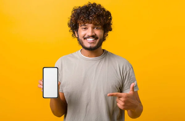 Θετικός χαρούμενος Ινδός δείχνει smartphone με λευκή κενή οθόνη, δείχνει το δάχτυλο σε αυτό — Φωτογραφία Αρχείου