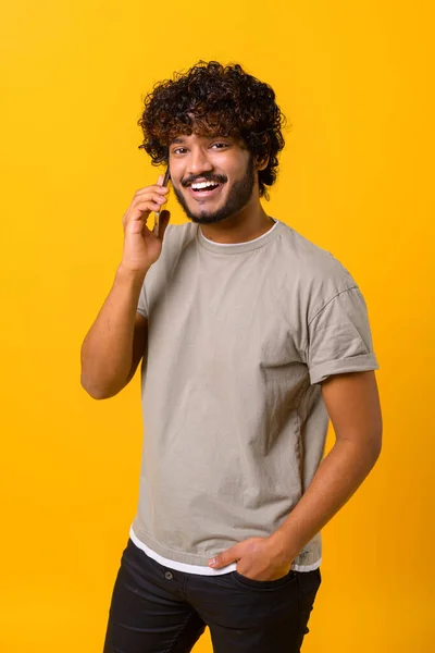 Νεαρός Ινδός μιλάει στο τηλέφωνο, τηλεφωνεί σε κάποιον, κοιτάζει την κάμερα με χαρούμενο χαμόγελο — Φωτογραφία Αρχείου