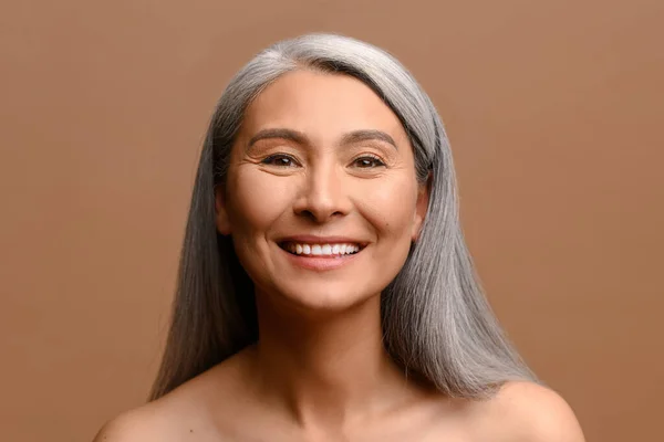 Asian mature magnificent grey-haired woman isolated on brown background — ストック写真
