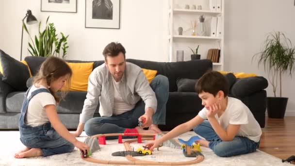 Far og børn tilbringer weekenden sammen hjemme, forældre og to børn leger legetøj – Stock-video