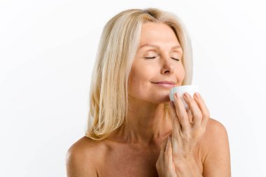 Hassas orta yaşlı kadın elinde bir kavanoz dolusu nemlendirici zengin krem tutuyor.