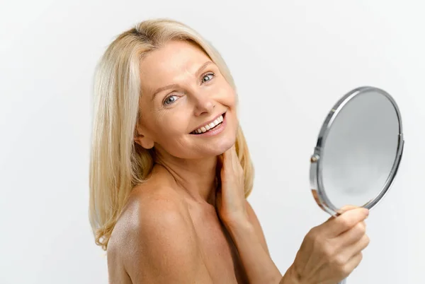 Jasna i urocza blondynka w średnim wieku trzymająca lustro kosmetyczne — Zdjęcie stockowe