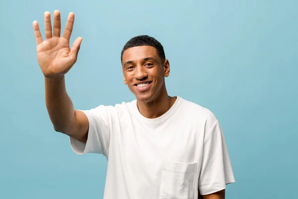 Freundlicher junger afrikanisch-amerikanischer Typ in weißem lässigem T-Shirt, der mit der Hand wedelt — Stockfoto