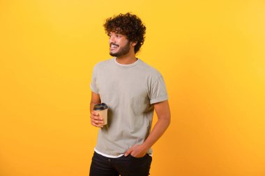 Günlük tişörtlü, kıvırcık saçlı, yakışıklı Hintli genç adam kahve keyfi yapıyor.