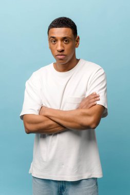 Beyaz tişört giyen, ciddi bir Afro-Amerikalı adamın dikey stüdyo fotoğrafı.