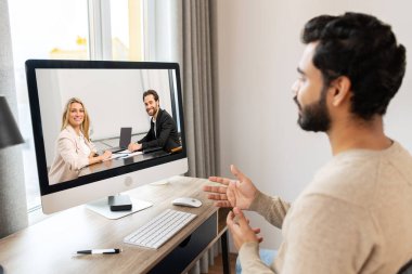 Serious concentrated pakistani male student involved virtual meeting, webinar. Man making video call on the computer, sitting at the table at home