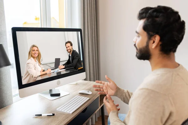 Serious concentrated pakistani male student involved virtual meeting, webinar. Man making video call on the computer, sitting at the table at home — 스톡 사진