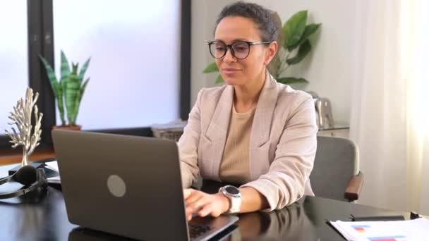 Geconcentreerde jonge kantoormedewerker zakenvrouw met bril zittend aan het bureau in het kantoor — Stockvideo