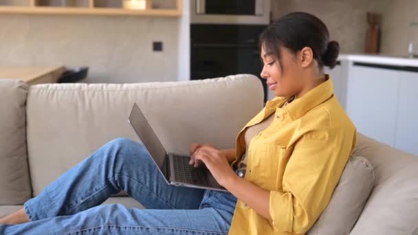 Jeune multiracial belle femme utilisant ordinateur portable à la maison couché sur le canapé à la maison — Video