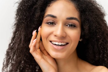 Sensual smiled woman holding hands with natural manicure near face isolated on white background. Enchanting lady touching face gently, enjoying her appearance