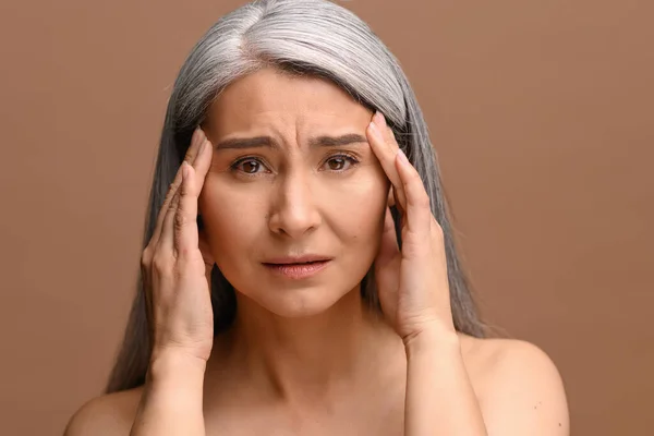 Middle-aged gray-haired Asian woman suffering from strong headache — стокове фото