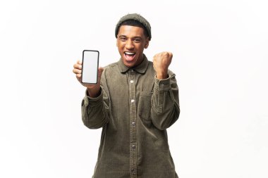 Akıllı telefonu tutan ve gülümseyen mutlu adam evet hareketi yapıyor, çevrimiçi piyangoyu kutluyor ya da zaferi ele veriyor. Beyaz üzerine kapalı stüdyo çekimi.