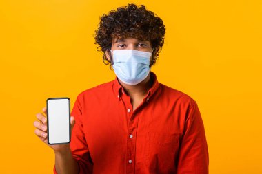 Çevrimiçi servis, teknoloji. Kameraya bakarken ayakta duran ve cep telefonu tutan mutlu genç adamın portresi. Stüdyoda çekim izole edildi