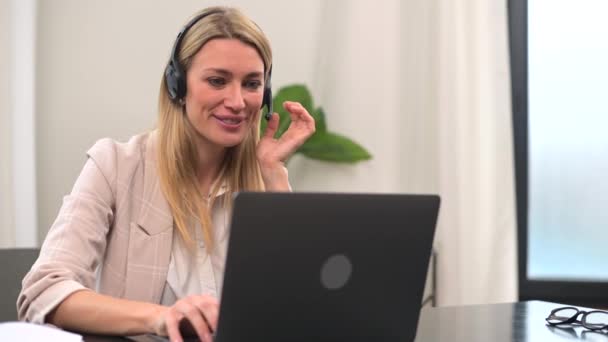 Operadora de centro de llamadas femenino joven con auriculares manos libres hablando con el cliente — Vídeos de Stock